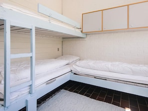 A bunk bed room with a white mattress, a grey rug, and a white brick wall.