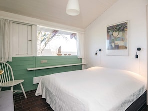 A room with a bed, a chair, a window with curtains, a wall-mounted lamp, and a painting. - 5 Person Holiday Home in Aabenraa (Aabenraa)