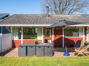 A house with a tiled roof, a covered patio with a table and chairs, and a window with curtains. - 5 Person Holiday Home in Aabenraa (Aabenraa)