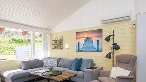 A living room with a sofa, armchair, coffee table, and a painting of a pier. - 5 Person Holiday Home in Aabenraa (Aabenraa)