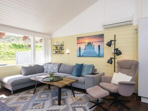 A living room with a sofa, armchair, coffee table, and a painting of a pier. - 5 Person Holiday Home in Aabenraa (Aabenraa)