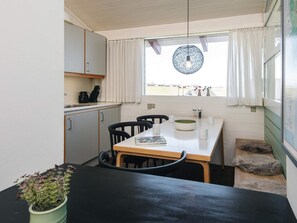 Une cuisine de taille réduite comprenant une table à manger, des chaises et une fenêtre avec des rideaux.