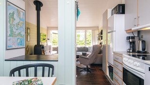 A compact kitchen with a stove, microwave, and dining area with chairs and a table. - 5 Person Holiday Home in Aabenraa (Aabenraa)