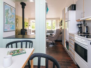 A compact kitchen with a stove, microwave, and dining area with chairs and a table. - 5 Person Holiday Home in Aabenraa (Aabenraa)