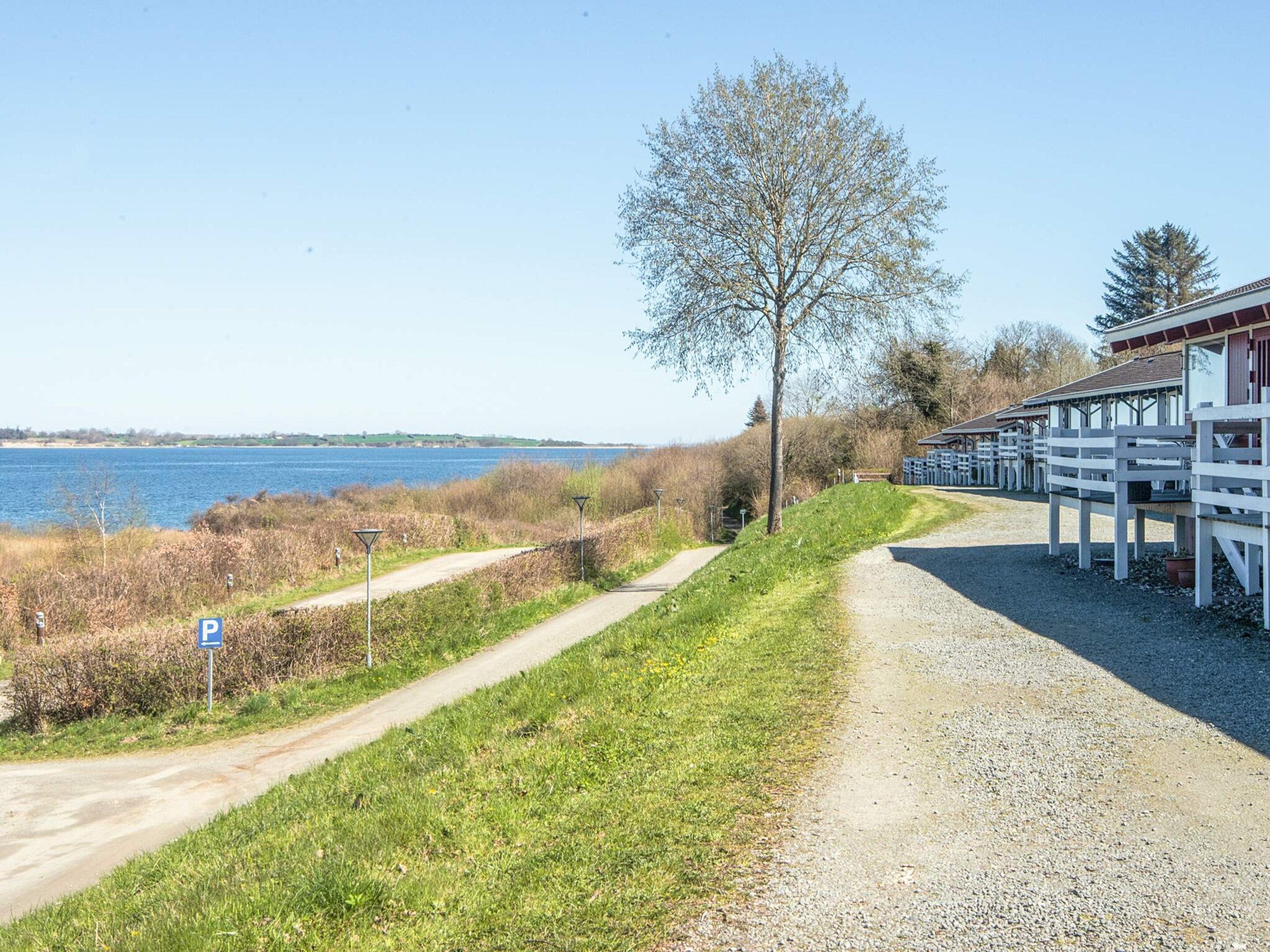 En grusvej fører hen til en bygning med udsigt over vandet.