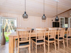 A wooden dining area with a table and chairs, pendant lights, and a view of the outdoors.