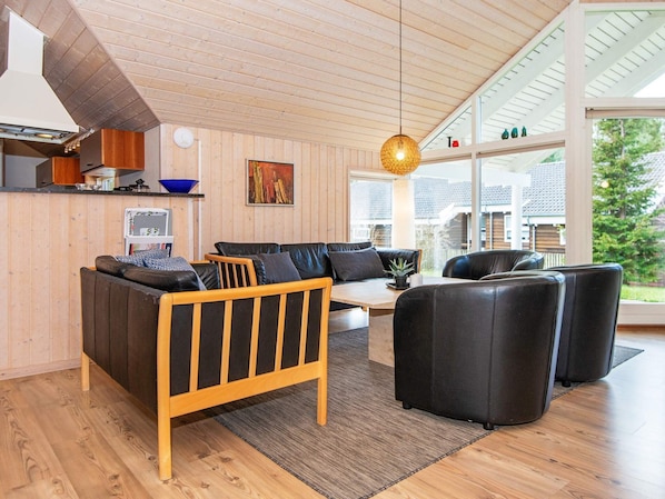 A modern living room with a wooden ceiling, a sofa set, a coffee table, and a hanging light fixture.