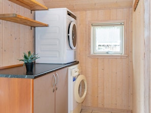 A compact laundry room with a washing machine, dryer, and a small window.