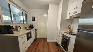A modern kitchen with white cabinets, stainless steel appliances, and a wooden floor. - Blue Lago at Raffertys Resort (Cams Wharf)
