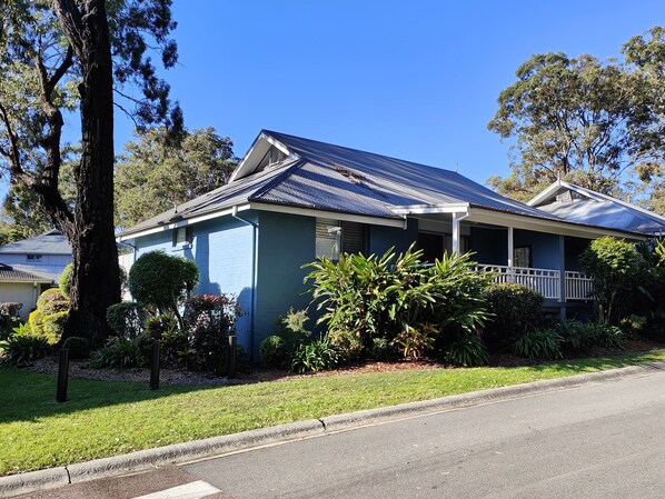 A single-story house with a blue exterior, a front porch, and a well-maintained lawn. - Blue Lago at Raffertys Resort (Cams Wharf)