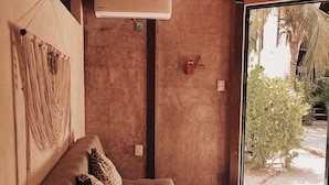 Un interno moderno con un divano marrone, un pannello decorativo in tessuto e vista sul verde circostante.
