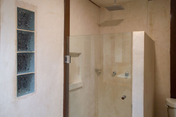 A glass-enclosed shower with a tiled wall, a visible showerhead, and a window with bubble patterns.