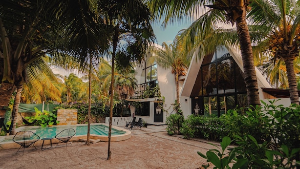 Una villa moderna con piscina, area relax esterna e rigogliosa vegetazione tropicale.