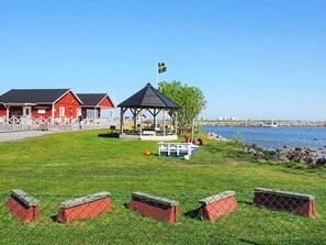 Ett område vid kusten med en röd byggnad som är märkt med texten ”INSEGLET”, ett lusthus och en inhägnad lekplats.