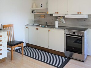 A kitchen with white cabinets, a Bosch oven, a wooden chair, and a striped rug. - 5 Person Holiday Home in Solvesborg (Sölvesborg)