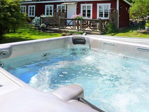 Ett bubbelbad med en trädeck och en röd byggnad i bakgrunden.