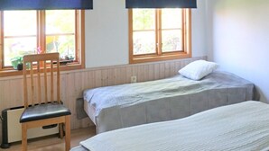 Una habitación con dos camas, una silla y un ventanal con vistas a zonas verdes.