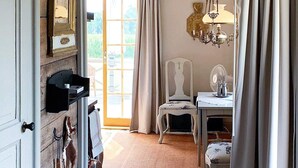A room with a wooden door, a white chair, a table with a lamp, and a chandelier. - 6 Person Holiday Home in Soderakra (Soderakra)