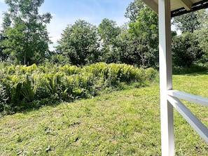 A grassy area with a white structure, possibly a gazebo, and dense green foliage in the background. - 4 Person Holiday Home in Braas (Braås)