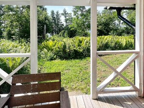 A wooden bench under a white pergola overlooking a garden with ferns and grass. - 4 Person Holiday Home in Braas (Braås)