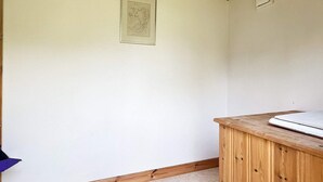 Una habitació amb un armari de fusta, un quadre al mur i un terra amb moqueta.