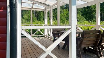 A covered outdoor deck with wooden flooring and benches.