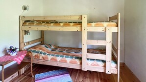 Un llit superposat amb un estovat estampat, una taula petita amb un ram i un terra de fusta.