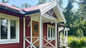 A red wooden house with a porch, white trim, and a single door. - 4 Person Holiday Home in Braas (Braås)