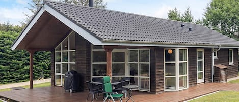 Una casa moderna con una amplia terraza, una zona de estar exterior cubierta y una chimenea.