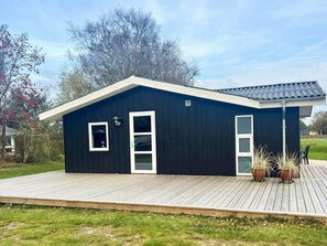 A single-story building with a dark exterior, white trim, and a flat roof. - 4 Star Holiday Home in Saeby (Sæby)