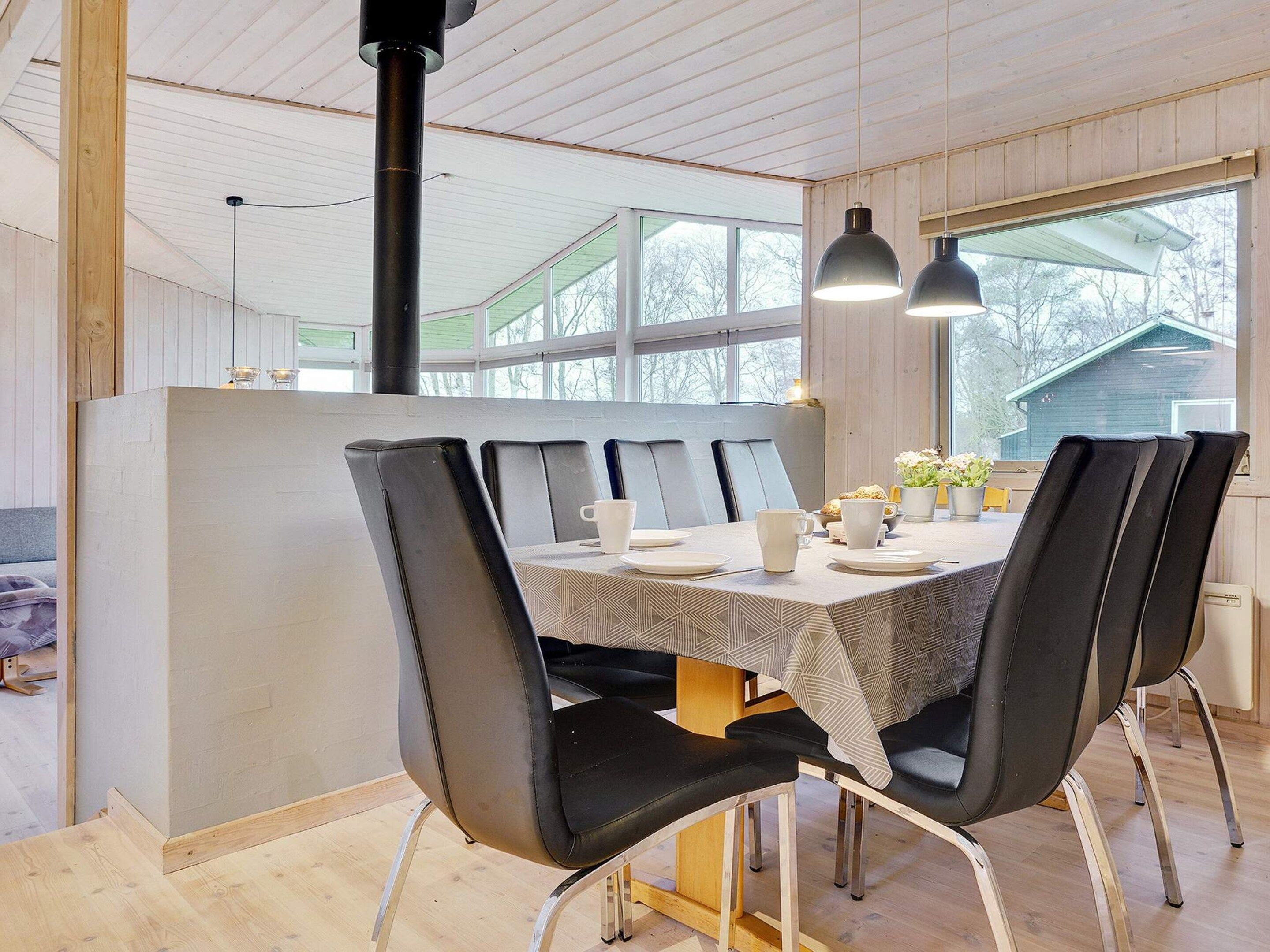 A dining area with a table set for four, surrounded by black chairs with metal legs.