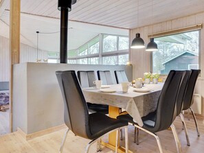 Espaço de jantar com mesa posta para quatro pessoas, rodeada por cadeiras pretas com pés de metal.