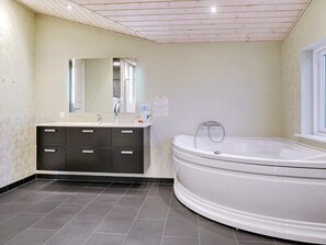 Une salle de bain moderne avec une baignoire sur pieds, un meuble-lavabo avec un miroir et un sol carrelé.