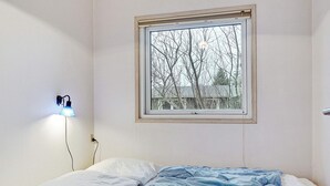 A bedroom with a single bed, a window with a view of bare trees, and a wall-mounted lamp. - 4 Star Holiday Home in Saeby (Sæby)