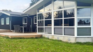 A modern house with a large glass extension, a deck with outdoor furniture, and a well-maintained lawn. - 4 Star Holiday Home in Saeby (Sæby)