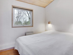 Ein Schlafzimmer mit einem Bett, einem Fenster, einer Heizung und einer Wandlampe.
