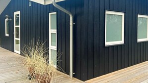 A modern building with a dark exterior, white-framed windows, and a visible gutter system. - 4 Star Holiday Home in Saeby (Sæby)