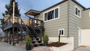 A two-story house with a wooden deck and a staircase leading to the upper floor.