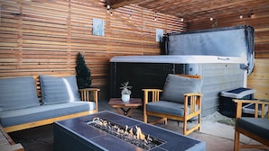 An outdoor seating area with wooden slats, a fire pit, and a grill.
