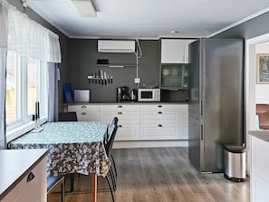 A compact kitchen with white cabinets, a microwave, and a stainless steel refrigerator. - 6 Person Holiday Home in Fiska-by Traum (Vanylven)