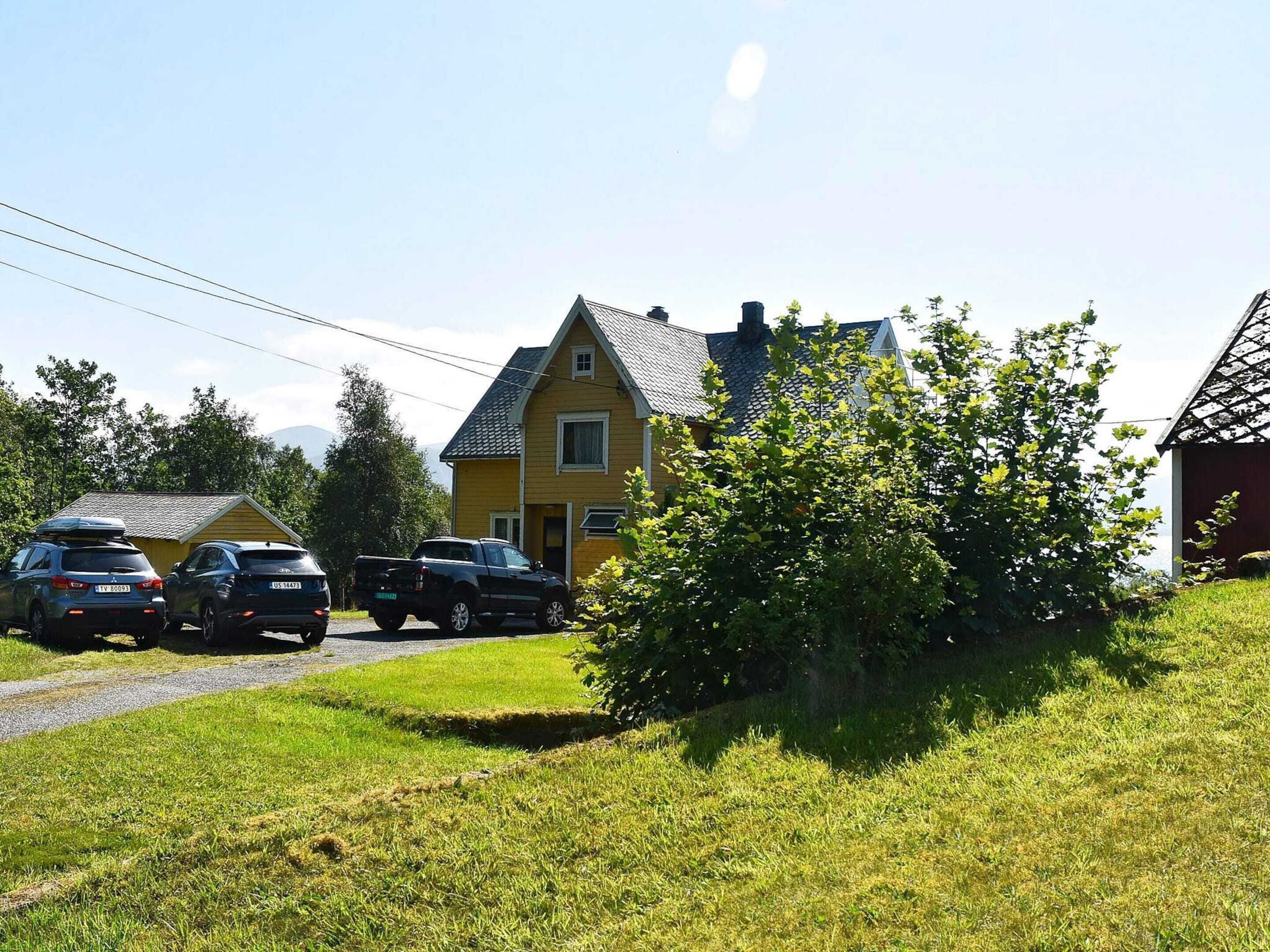 A two-story house with a sloped roof, a driveway, and parked cars.
