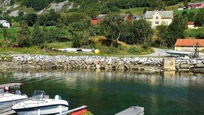A marina with boats docked, a rocky shoreline, and houses in the background. - 6 Person Holiday Home in Fiska (Vanylven)
