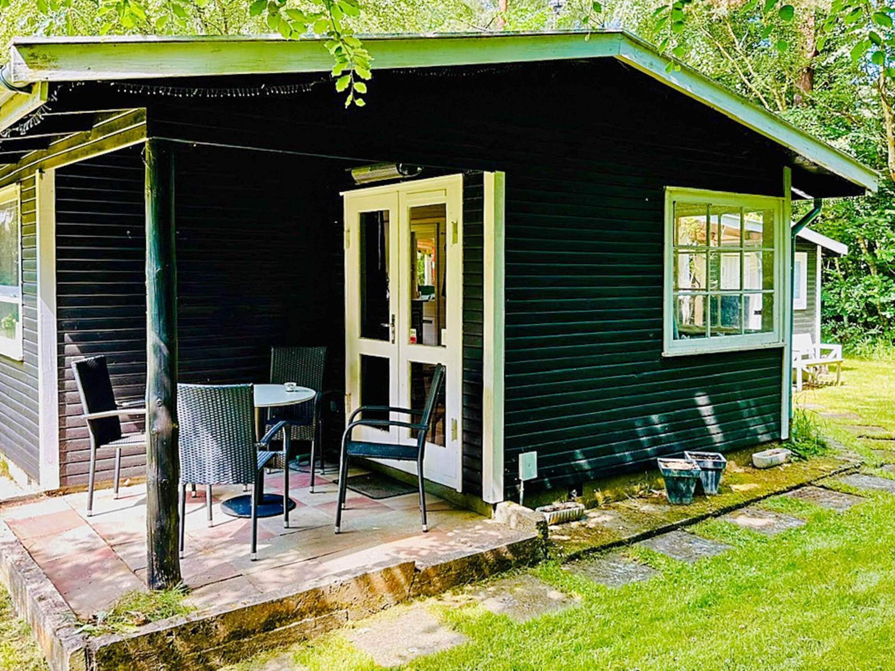 A small house with a porch, a table, and chairs.