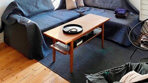 Et værelse med en blå sofa, et træbord og en stol.