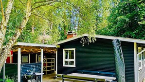 En lille bygning i et enkelt plan med en overdækket veranda, grill og et picnicbord.