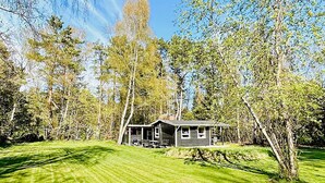A single-story house with a porch, surrounded by a well-maintained lawn and trees. - 4 Person Holiday Home in Frederiksvaerk (Frederiksvaerk)