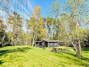 A single-story house with a porch, surrounded by a well-maintained lawn and trees.
