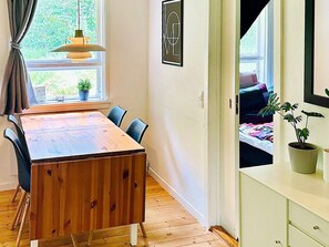 A room with a wooden dining table, chairs, a potted plant, and a bed with a view. - 4 Person Holiday Home in Frederiksvaerk (Frederiksvaerk)