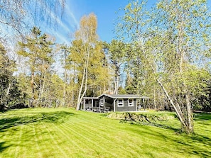 Yhden kerroksen talo, jossa on kuisti, ja sen ympärillä on hyvin hoidettu nurmikko ja puita.