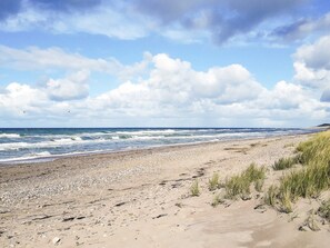 A beach with a rocky shoreline, waves, and a partly cloudy sky. - 4 Person Holiday Home in Frederiksvaerk (Frederiksvaerk)